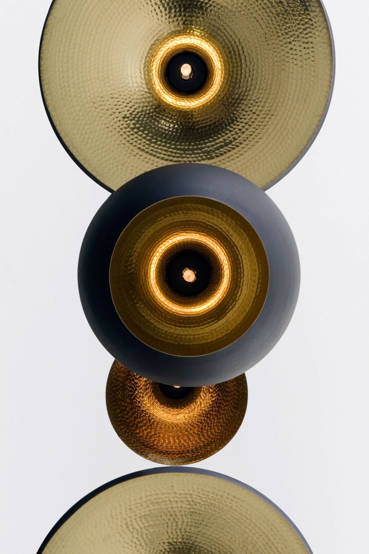 Nahaufnahme der Tom Dixon Beat Wandleuchte mit gehämmertem Messingschirm und warmem Lichtschein.
