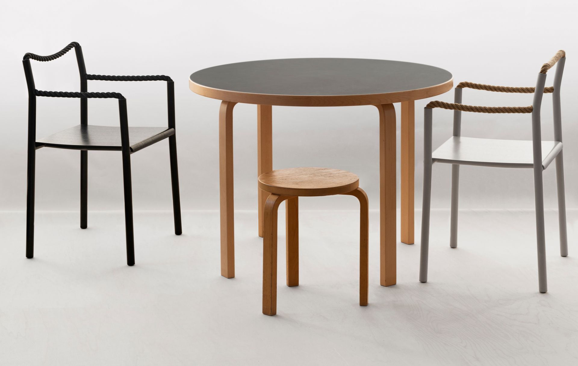 Artek Rope Chair Stühle in Schwarz und Grau mit Holztisch und Hocker im minimalistischen Design.
