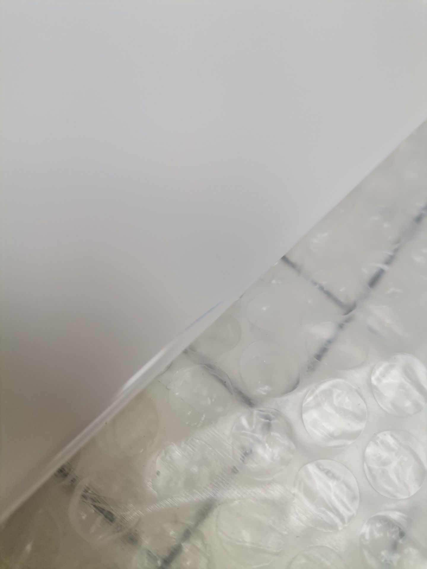Nahaufnahme von USM Haller Ersatzteilen (Mängelexemplar) verpackt in Luftpolsterfolie unter weißem Papier.