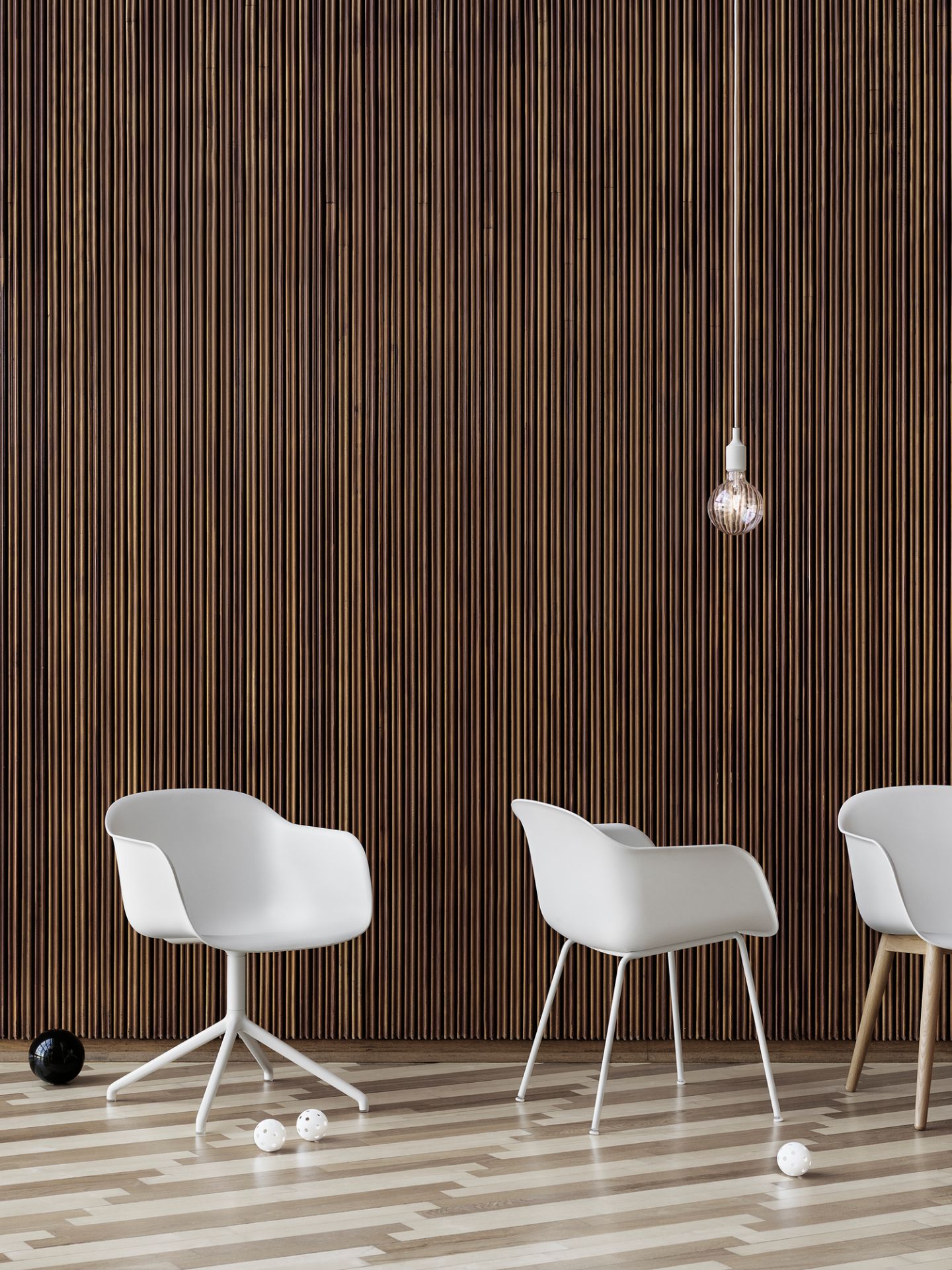 Weißer Fiber Armchair von Muuto mit Tube Base Gestell vor einer Holzpaneelwand.