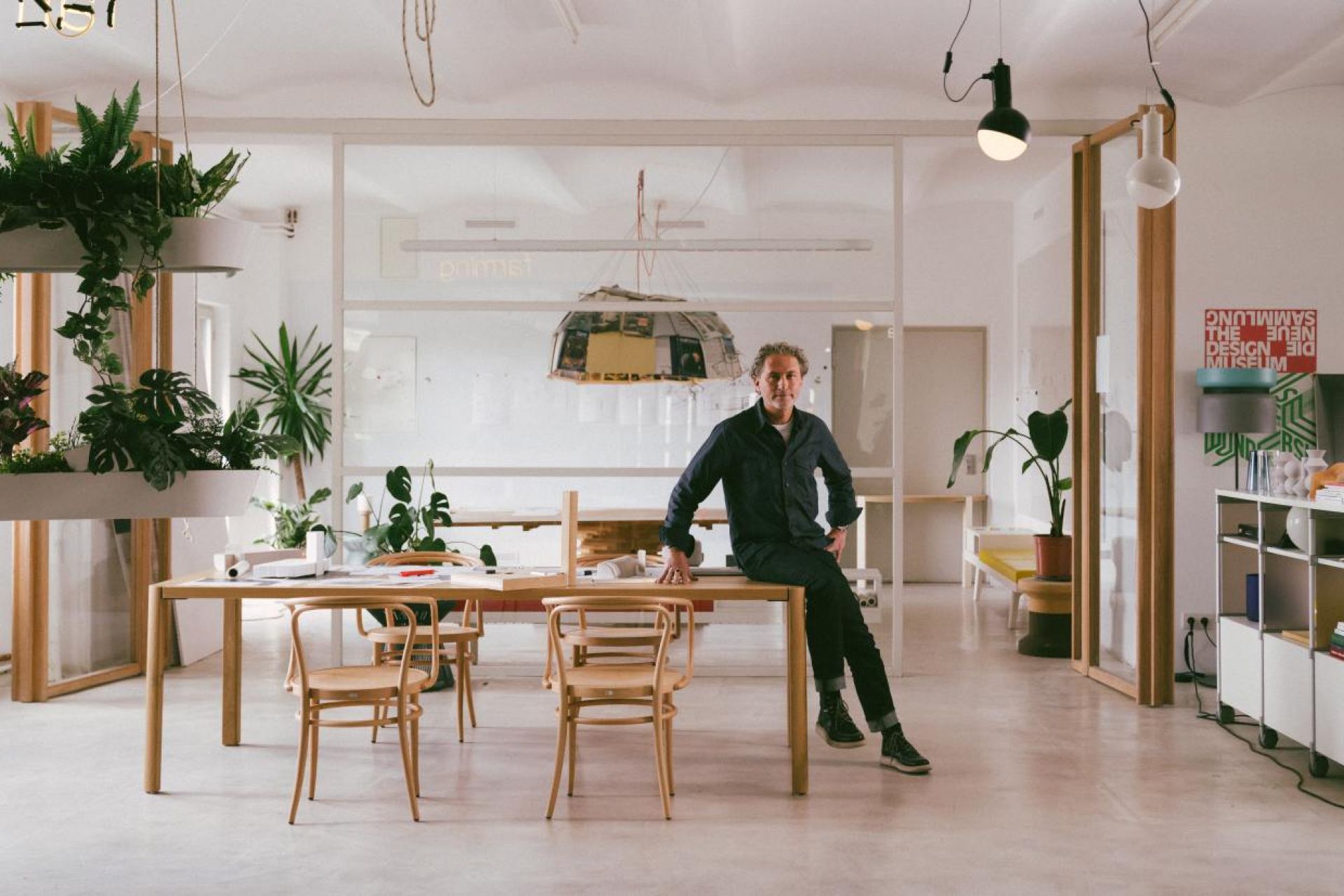 Heller Raum mit Thonet Esstisch 1140 aus Holz und passenden Stühlen, Person sitzt darauf.