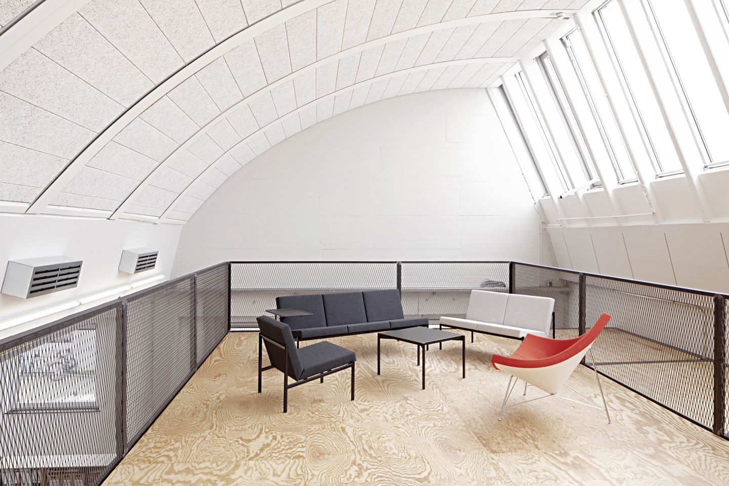 Heller Raum mit Vitra Coconut Chair in Rot-Weiß, Sofa, Sessel und Tisch auf hellem Holzboden.