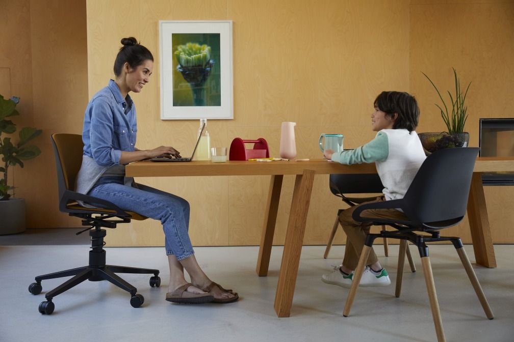 Frau arbeitet am Laptop auf einem Numo Task Bürostuhl von Aeris mit Rollen.