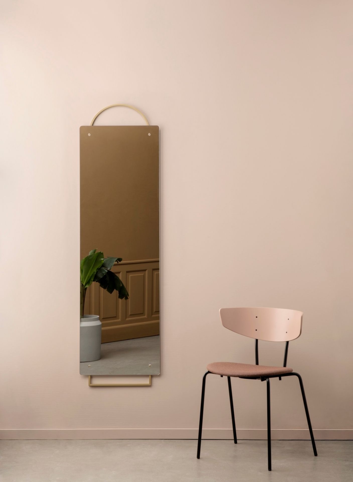 Großer, rechteckiger Adorn Spiegel von Ferm Living mit goldfarbenen Akzenten an der Wand, neben einem Stuhl.