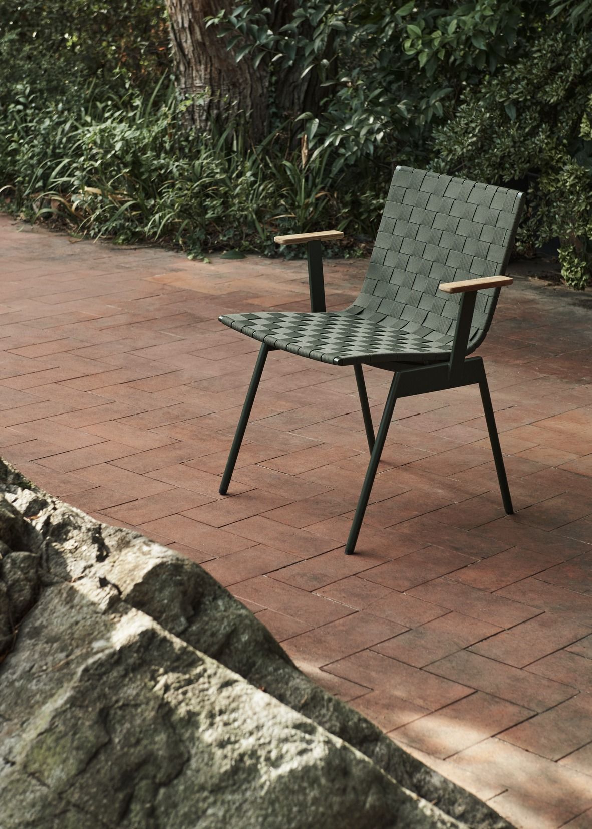 Ville AV34 Outdoor Chair Stuhl von AndTradition, grüner Gartenstuhl mit Holzarmlehnen auf Backsteinpflaster.