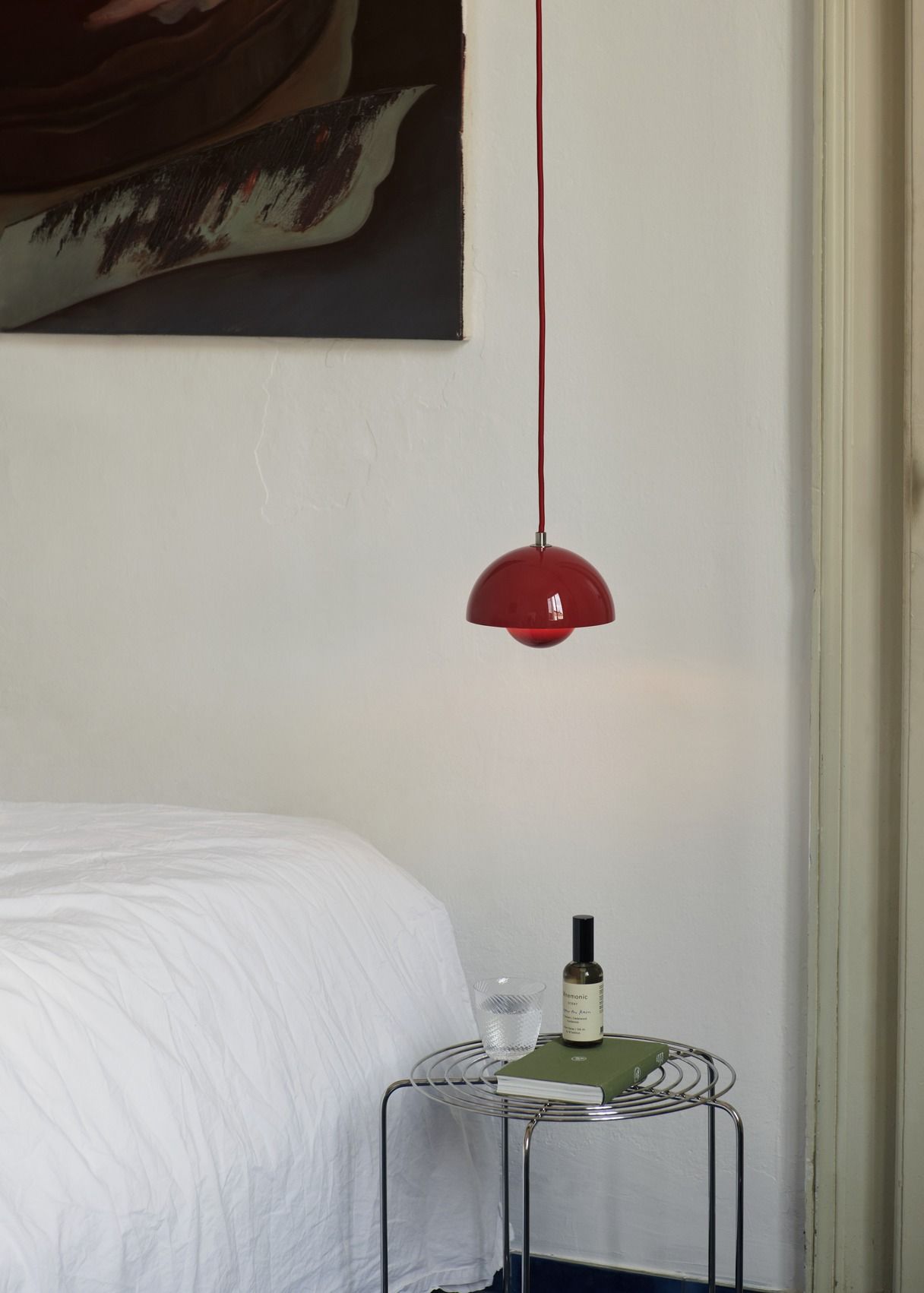 AndTradition Wire Stool VP11 als Beistelltisch im Schlafzimmer mit Buch, Glas und Duft.