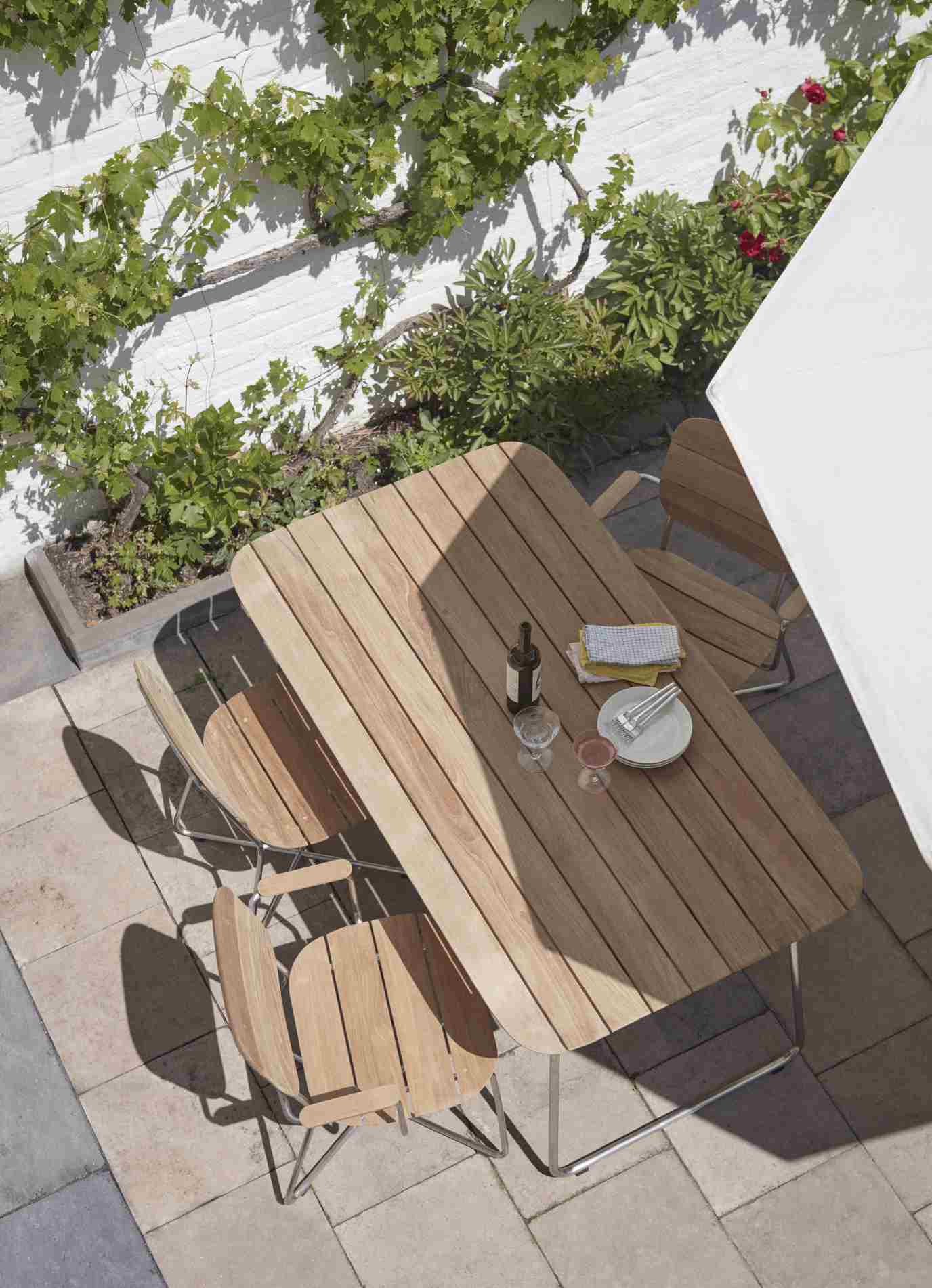 Lilium Armchair Armlehnenstuhl von Skagerak by Fritz Hansen im Garten mit Esstisch und Geschirr.