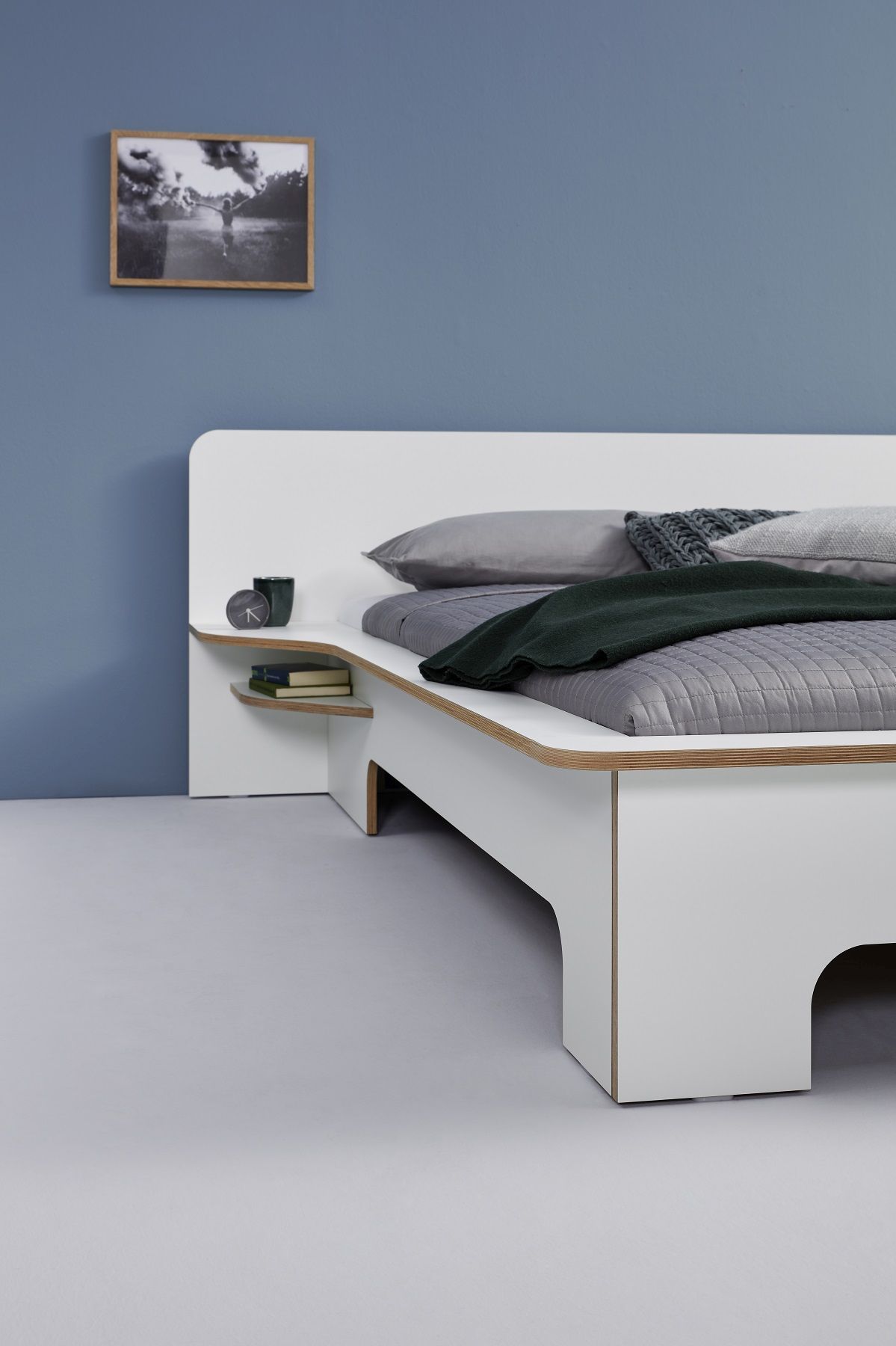 Plane Doppelbett von Müller Möbelwerkstätten in Weiß mit integriertem Nachttisch und Ablagefächern.