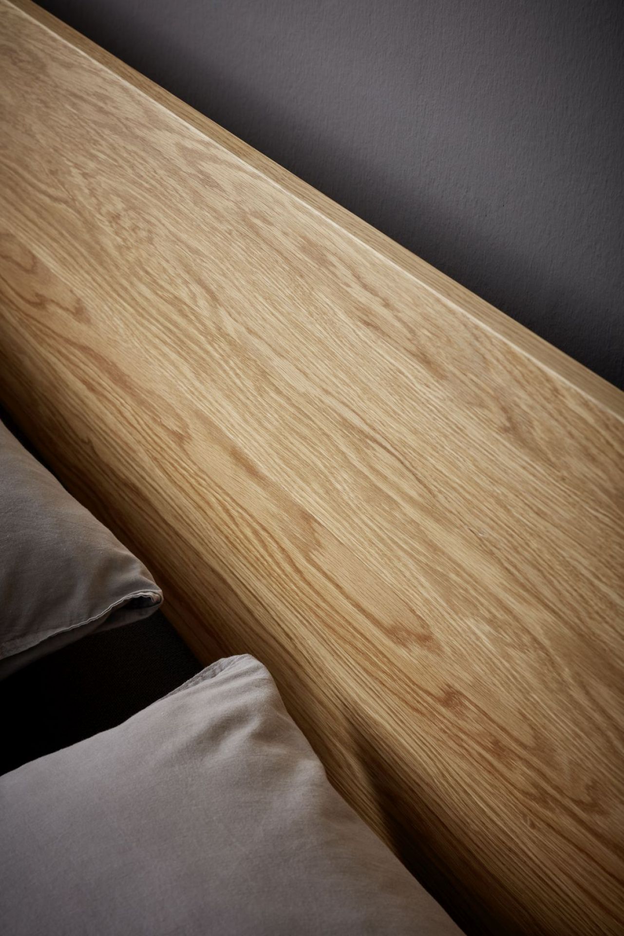 Detailaufnahme des Flai Bett Kopfteils aus Eiche von Müller Möbelwerkstätten mit Kissen.