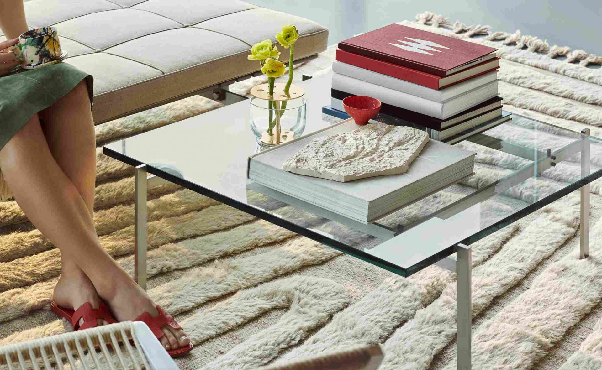 PK 61 Couchtisch von Fritz Hansen mit Glasplatte, Büchern und Dekoration in stilvollem Wohnambiente.
