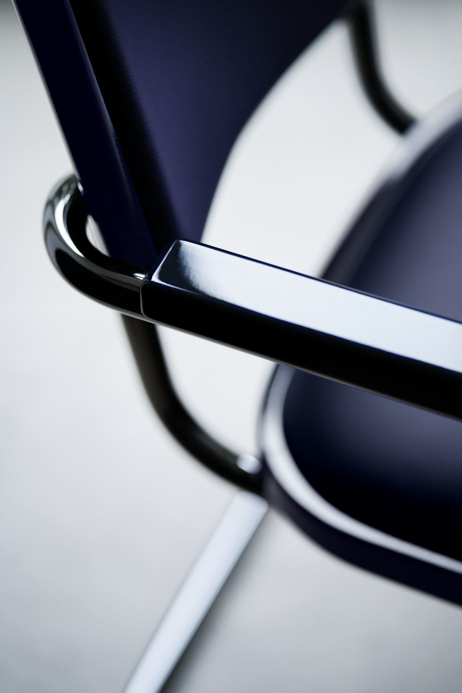 Detailaufnahme des JS. Thonet S 64 P Freischwinger Stuhls mit blauem Bezug und glänzendem, schwarzem Stahlrohrgestell.