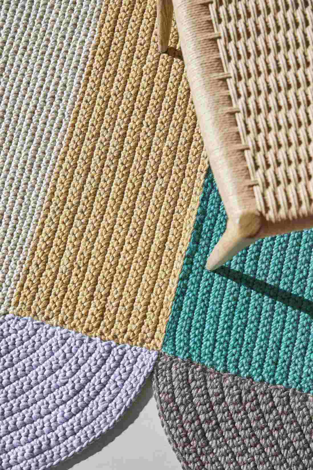 Detailaufnahme des The Crochet Collection Teppichs in verschiedenen Farben und Texturen neben einem Stuhl.