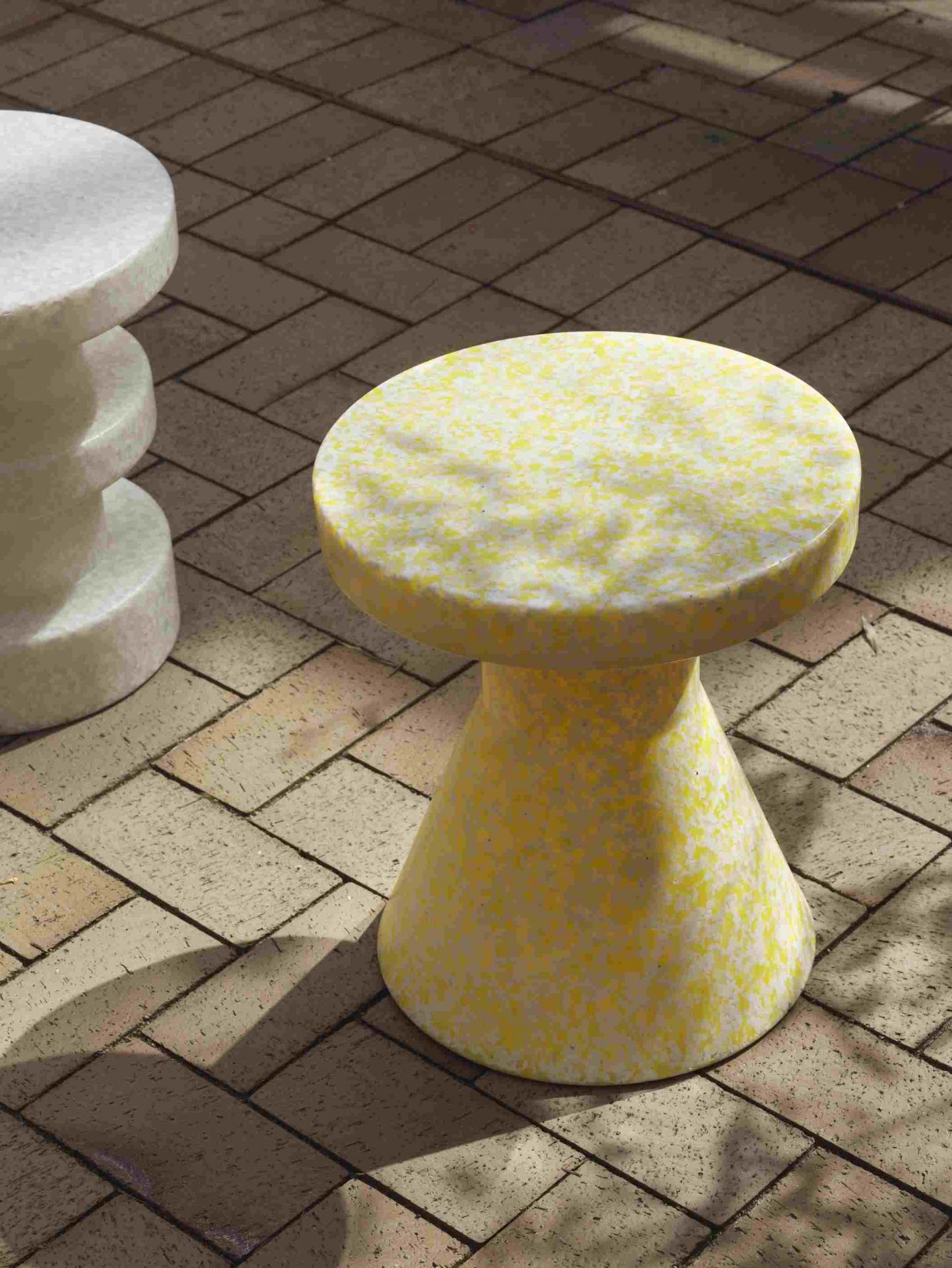 Gelber Bit Stool Cone Hocker von Normann Copenhagen auf Pflastersteinen, moderner Design Hocker.