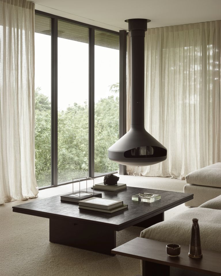 Ethnicraft Kabuki Beistelltisch aus dunklem Holz im modernen Wohnzimmer mit Kamin und großem Fenster.