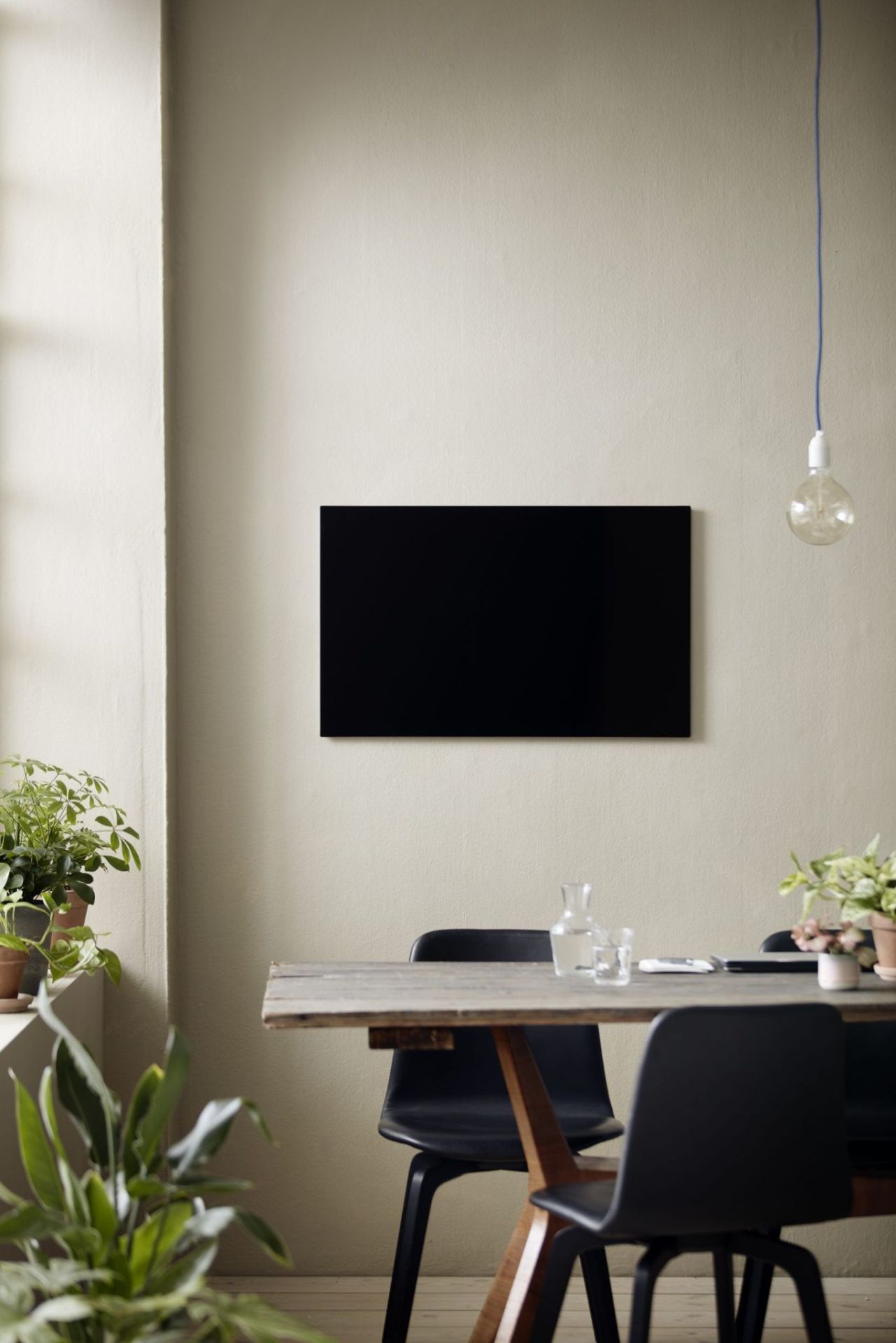 Schwarze Chat Board Classic Wand Glastafel magnetisch über einem Esstisch in einem modern eingerichteten Raum.
