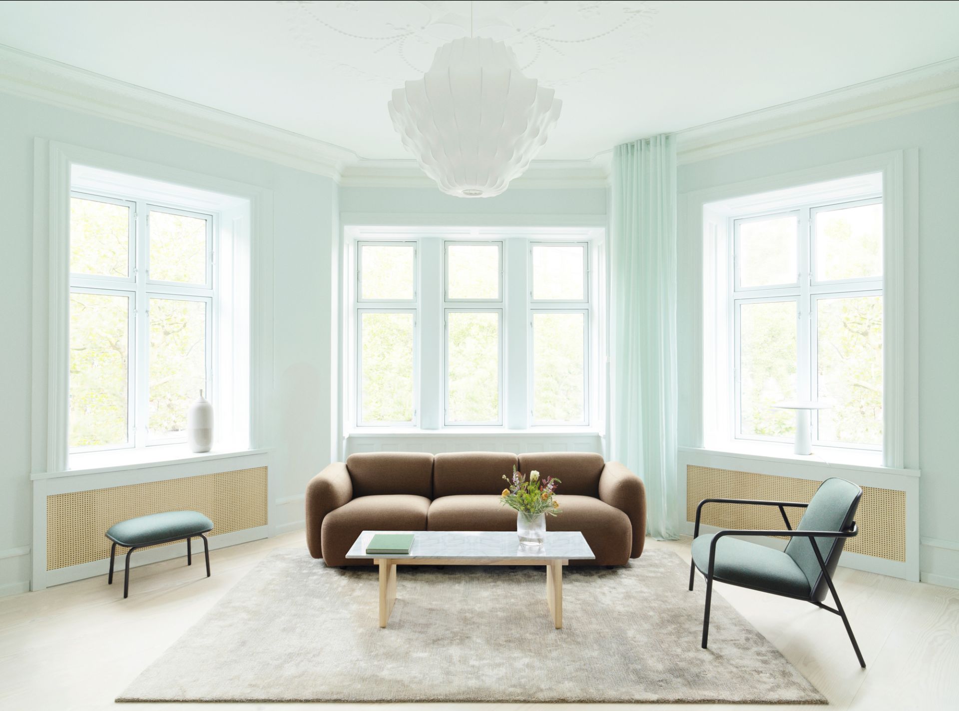 Helles Wohnzimmer mit Normann Copenhagen Phantom Lampe, Sofa, Teppich und Stühlen für ein modernes Interieur.
