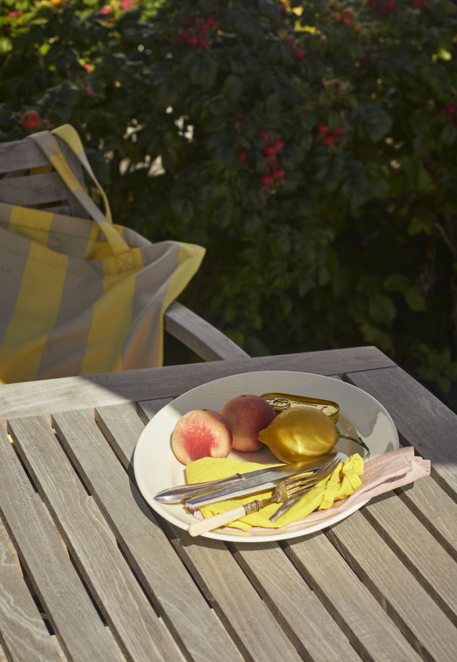 Ballare Tisch Outdoor von Skagerak by Fritz Hansen mit Pfirsichen, Zitrone und Besteck auf einem Teller.