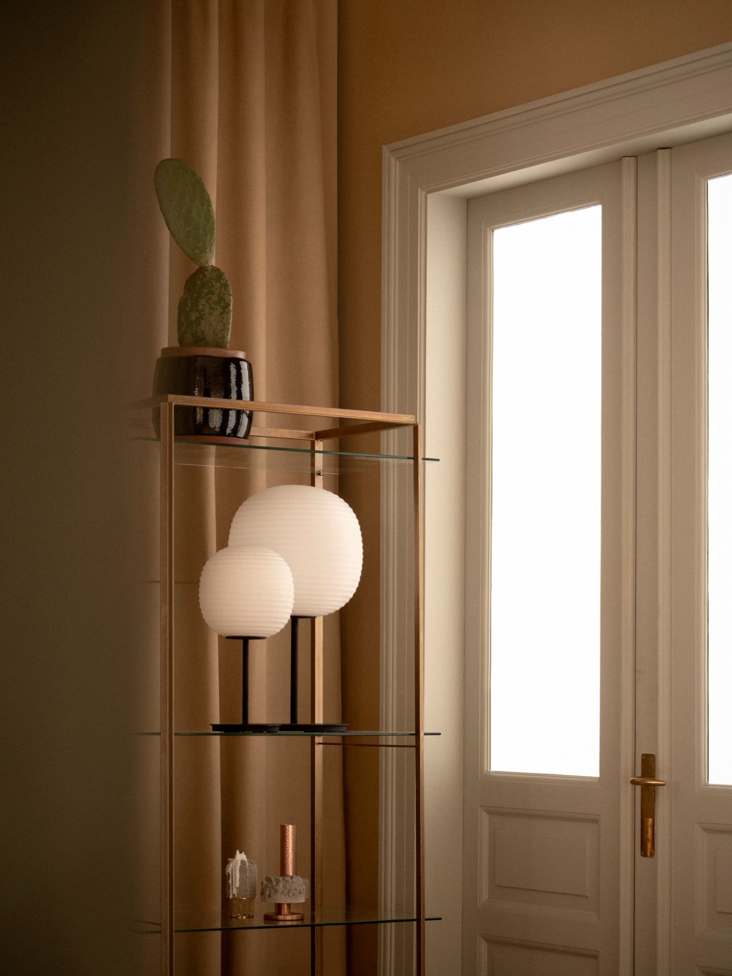 New Works Lantern Tischleuchte Mittel auf Regal mit Deko-Elementen, warmes, stimmungsvolles Licht.