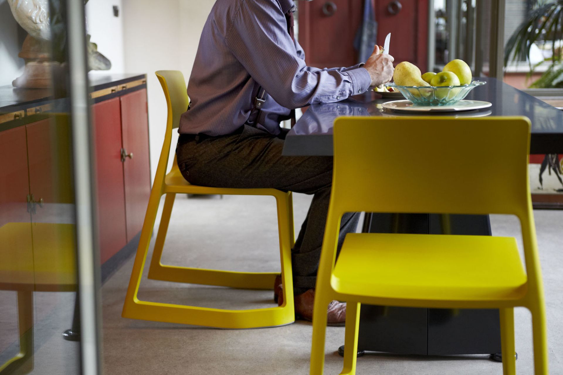 Gelber Tip Ton RE Stuhl von Vitra im modernen Esszimmer mit sitzender Person am Tisch.