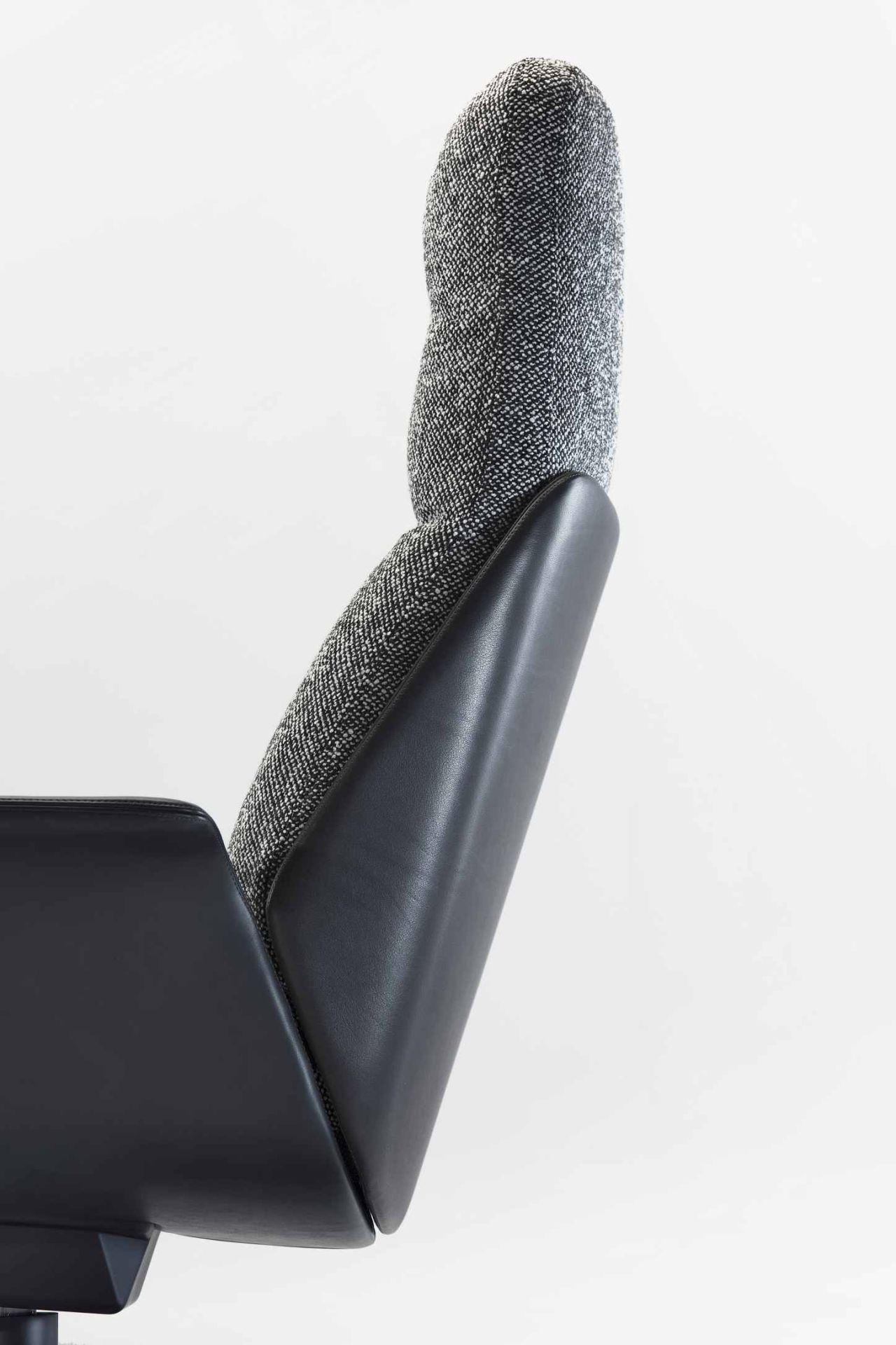 Detailaufnahme des Rei Sessel von Prostoria mit grau meliertem Stoffbezug und schwarzem Leder an der Rückenlehne.