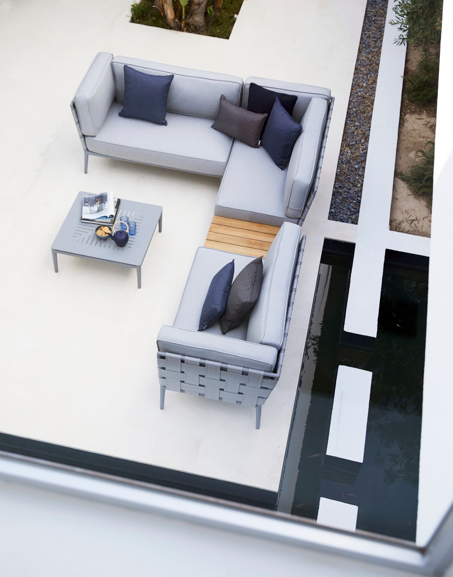 Luftaufnahme: Conic AirTouch Modulsofa rechts hellgrau von Cane-Line mit Outdoor-Tisch und Kissen.