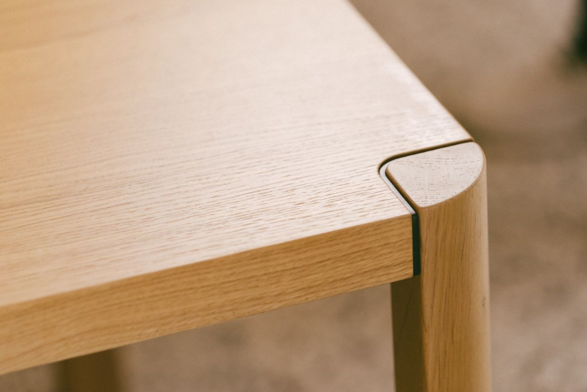 Detailaufnahme vom Thonet 1140 Esstisch: Tischplatte aus hellem Holz mit abgerundeter Ecke und Tischbein.