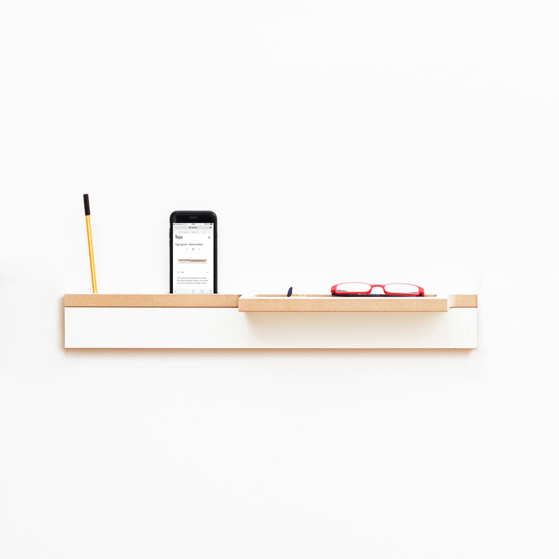 Tojo Grad Ablage: Wandregal in Weiß und Holz mit Stift, Handy und Brille.
