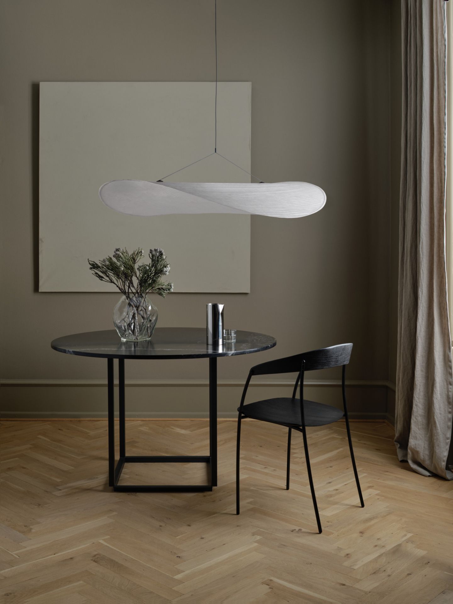 Moderne Tense Pendelleuchte von New Works über Esstisch mit Marmorplatte und schwarzem Stuhl.