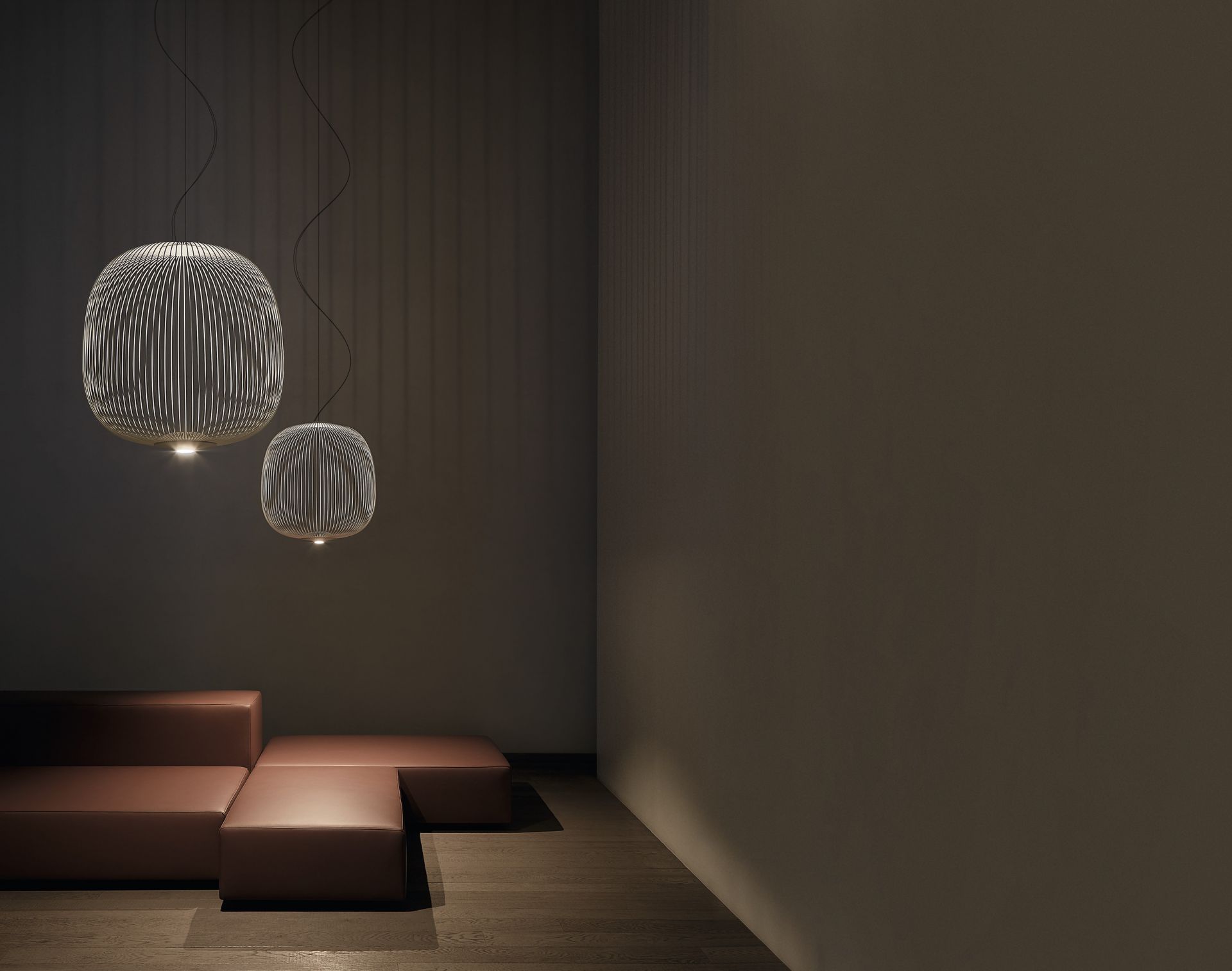 Zwei moderne Spokes 2 LED Pendelleuchten von Foscarini über braunem Ledersofa in dunklem Raum.