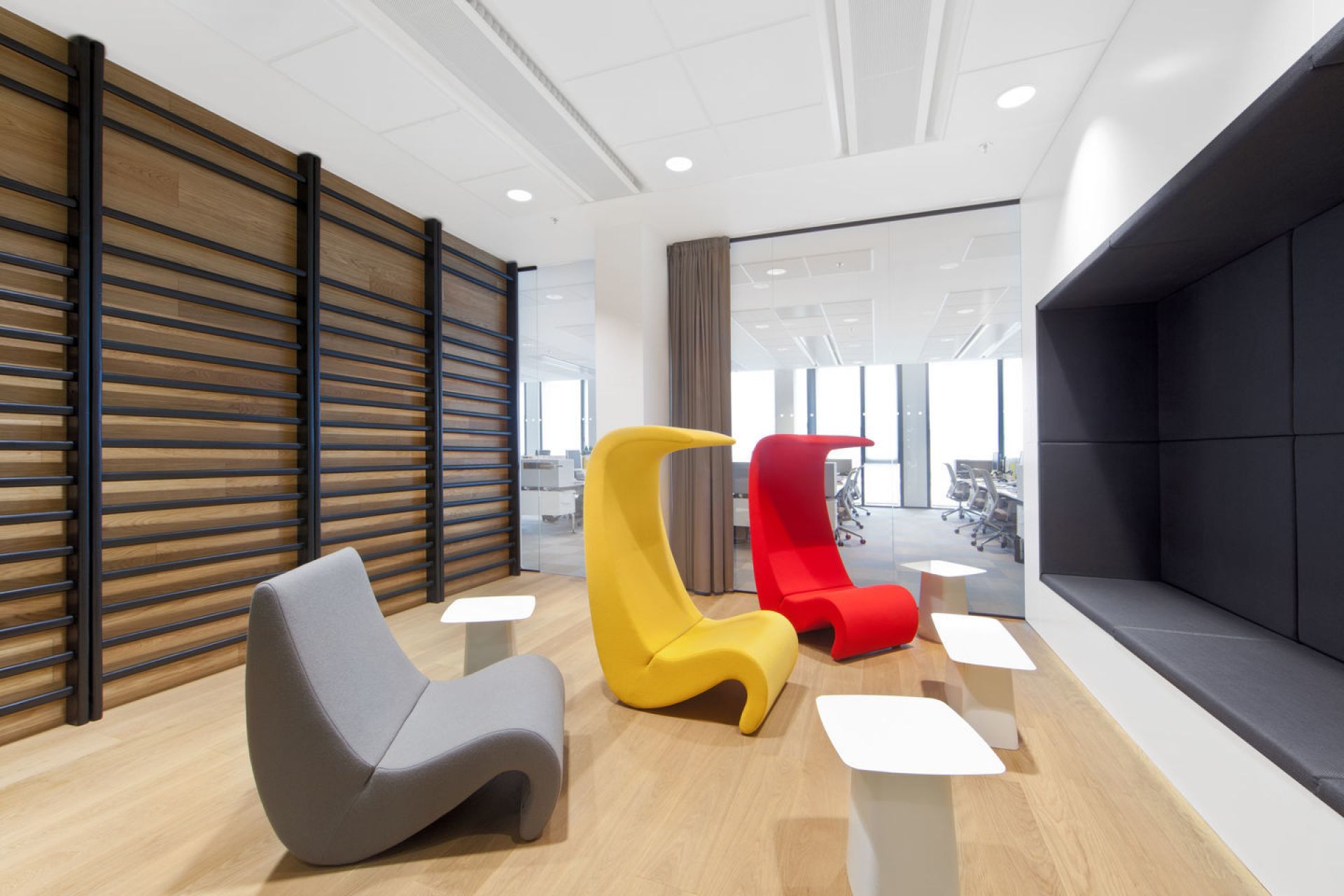 Büro-Lounge mit grauem Sessel, gelbem und rotem Vitra-Sessel und weißen Metal Side Table Beistelltischen.