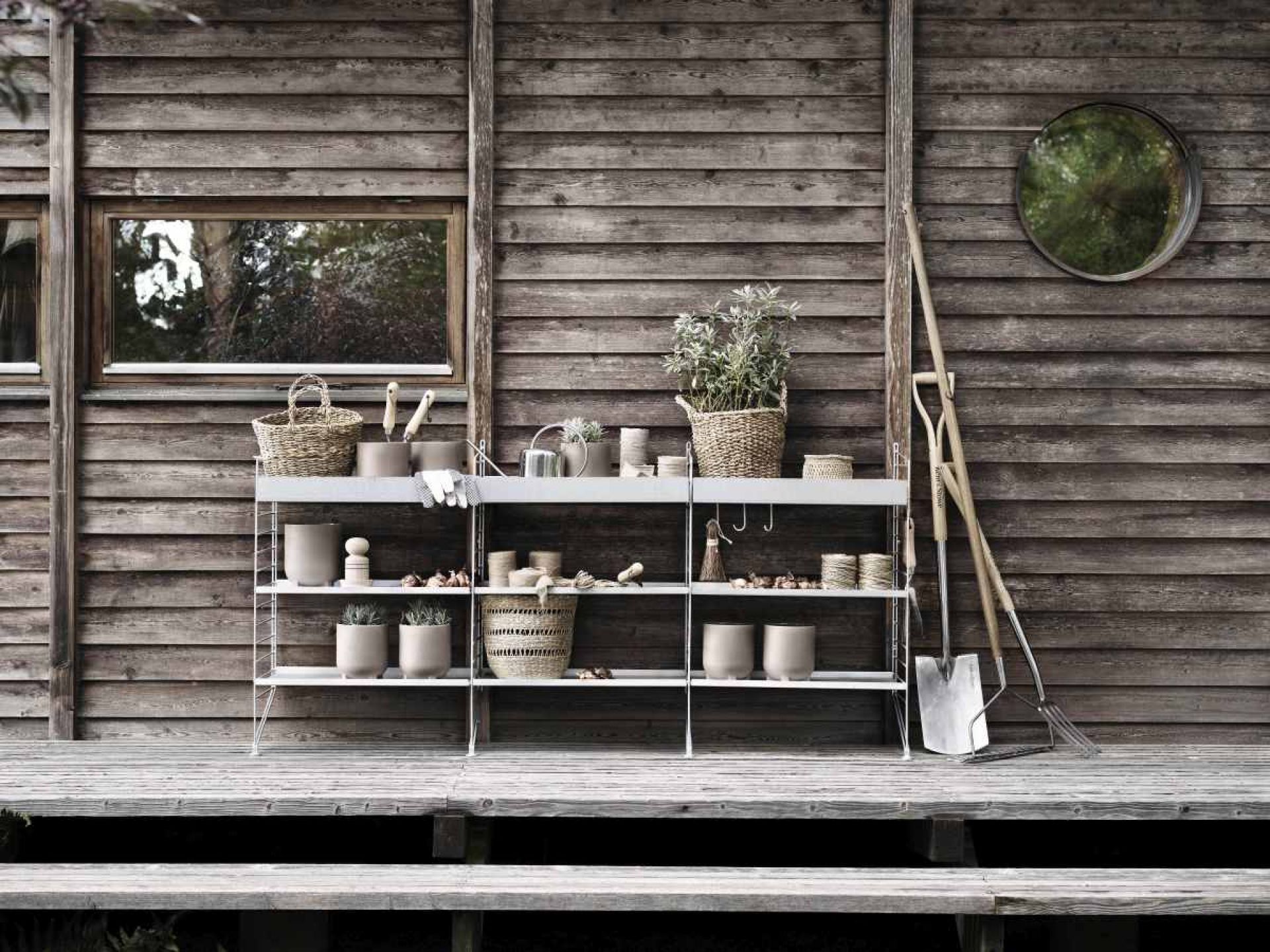 String Outdoor Regalsystem vor Holzwand mit Gartenzubehör, Bodenregal für Garten und Terrasse.