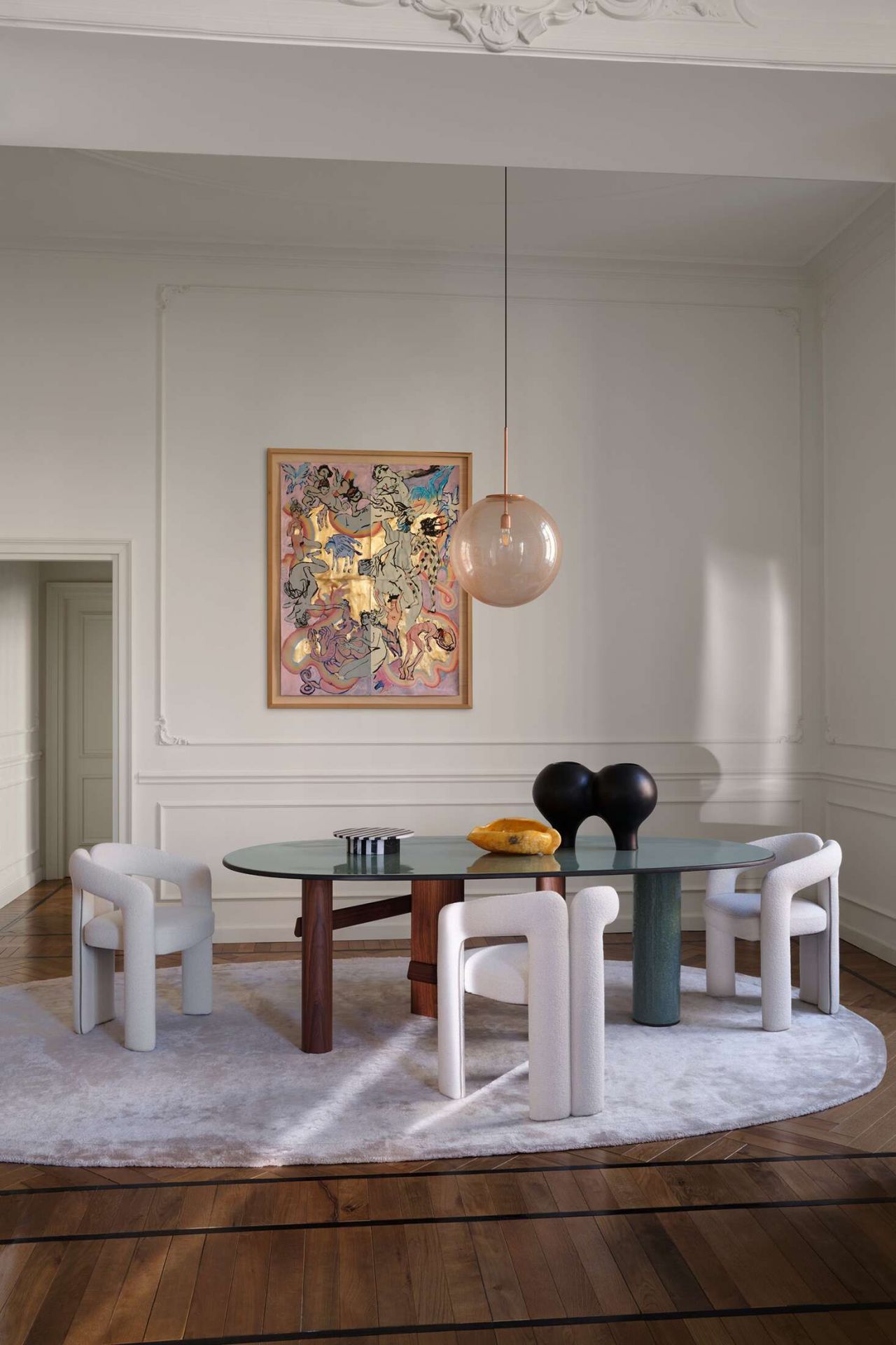 Esszimmer mit Cassina 562 Dudet Sessel, ovalem Tisch, Kunstwerk und Pendelleuchte für stilvolles Wohnen.