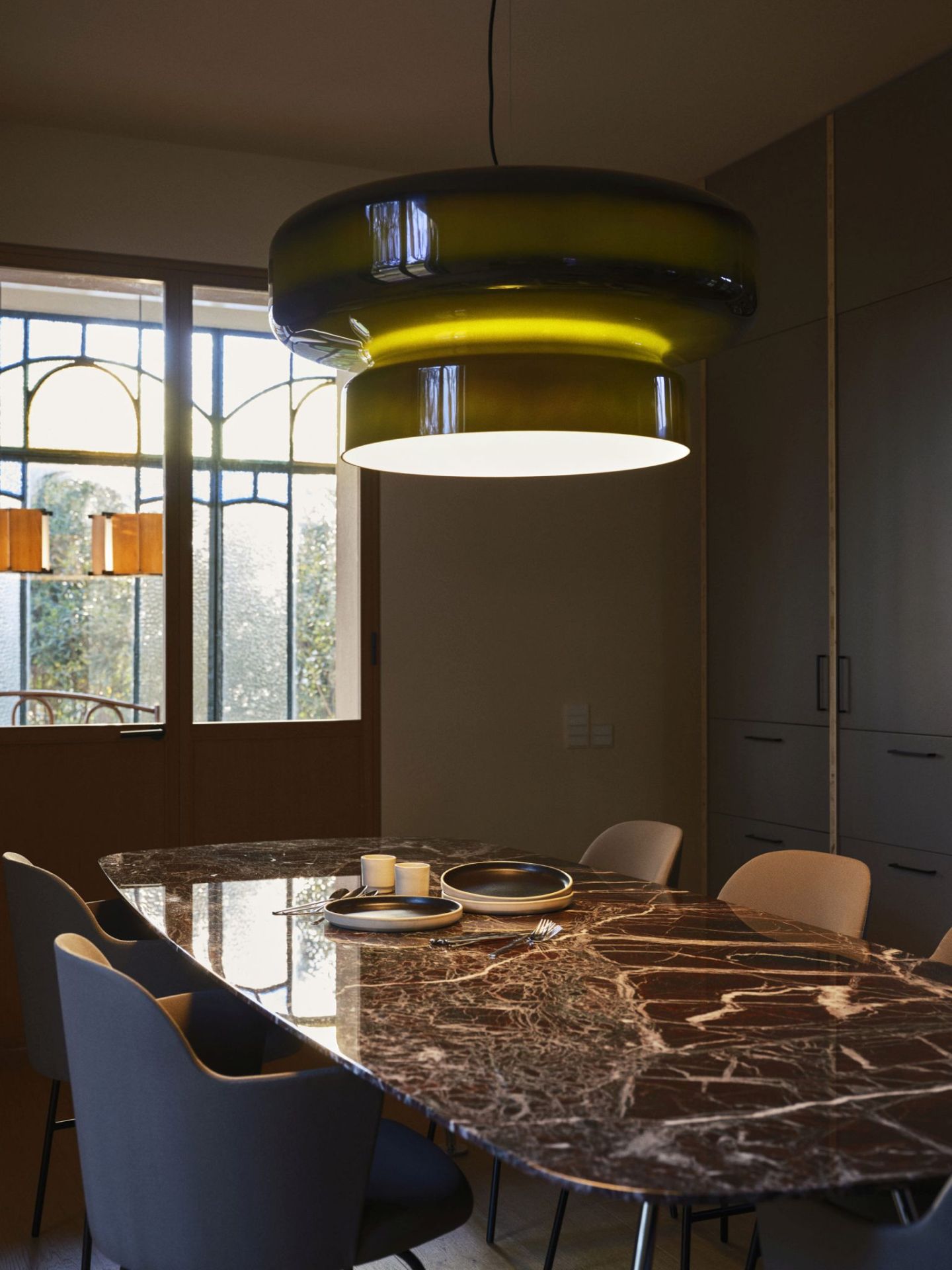 Bohemia Pendelleuchte in Rauchgrau von Marset über Esstisch mit Marmorplatte. Design Lampe.