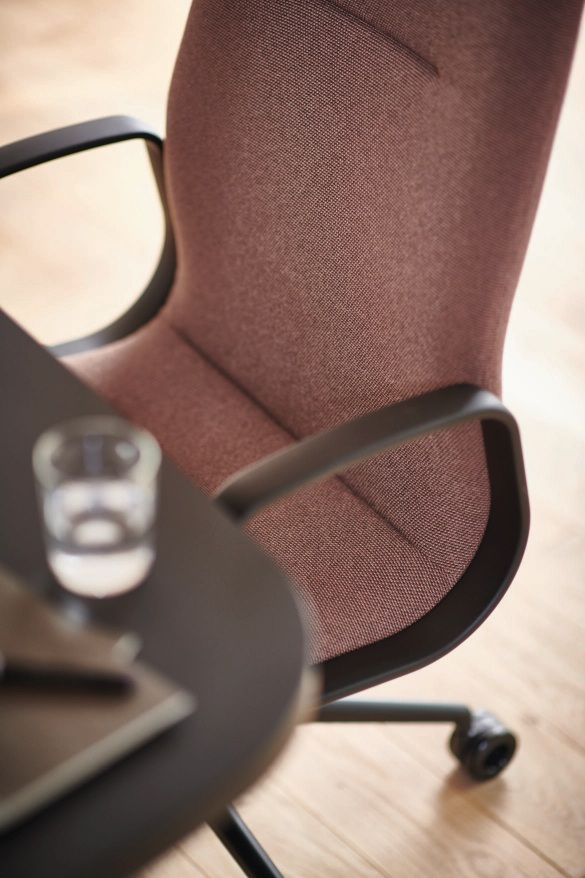 Detailaufnahme: Wilkhahn Decide Konferenzsessel mit braunem Stoffbezug, schwarzen Armlehnen und Rollen, ideal für moderne Büros.