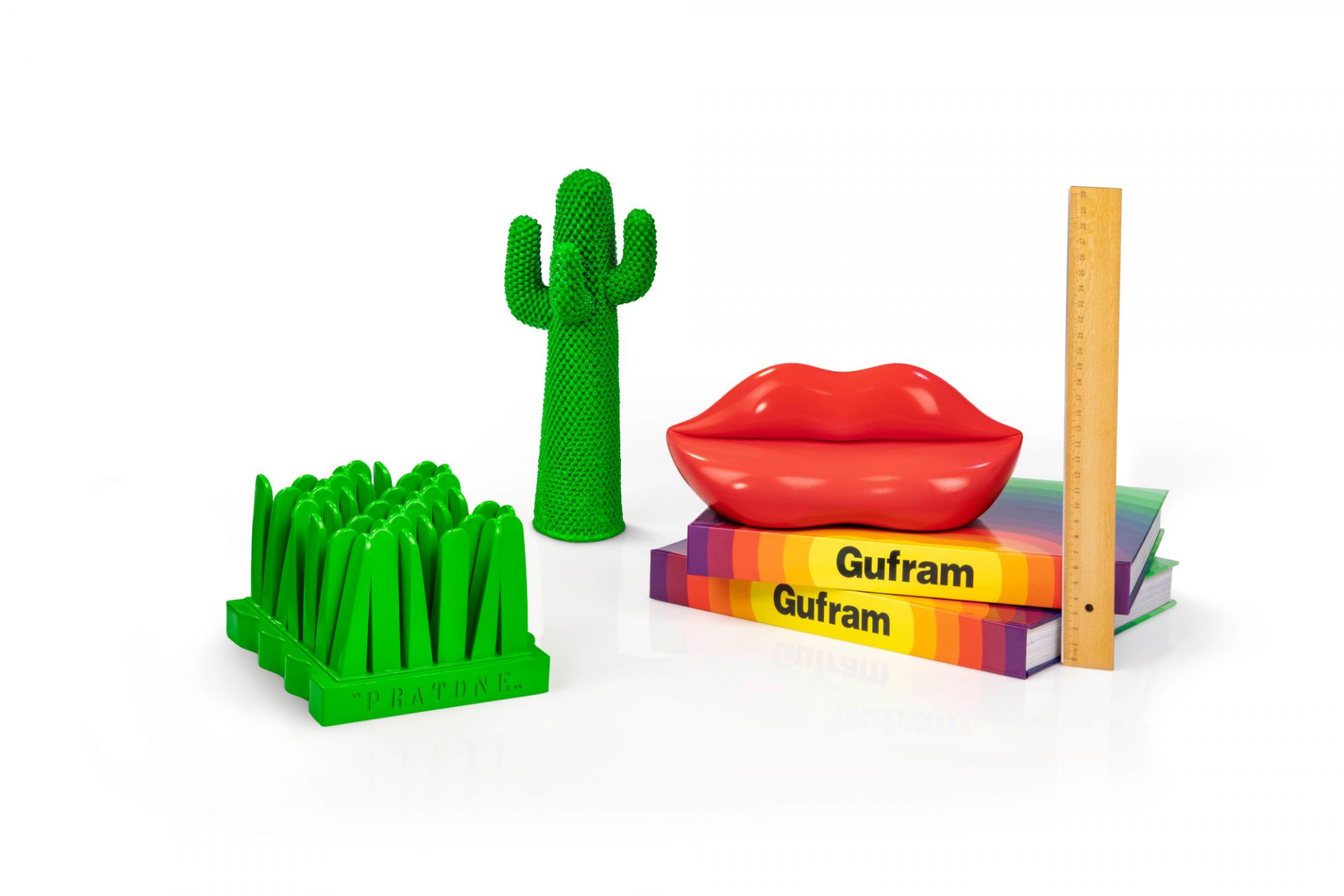 Guframini Bocca Miniatur, grüner Kaktus und Gras Designobjekt auf Büchern mit Lineal, modernes Wohnaccessoire.