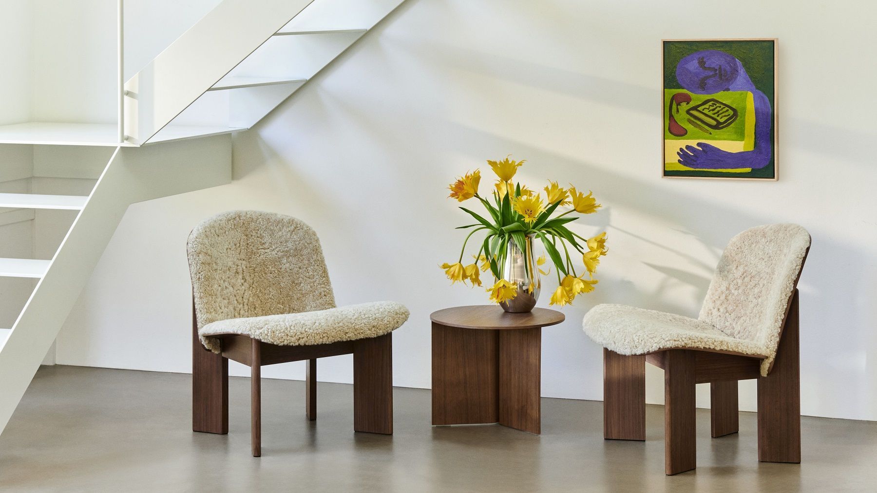 Zwei Stühle und ein Hay Slit Table Wood Round Beistelltisch aus Holz mit Blumen.