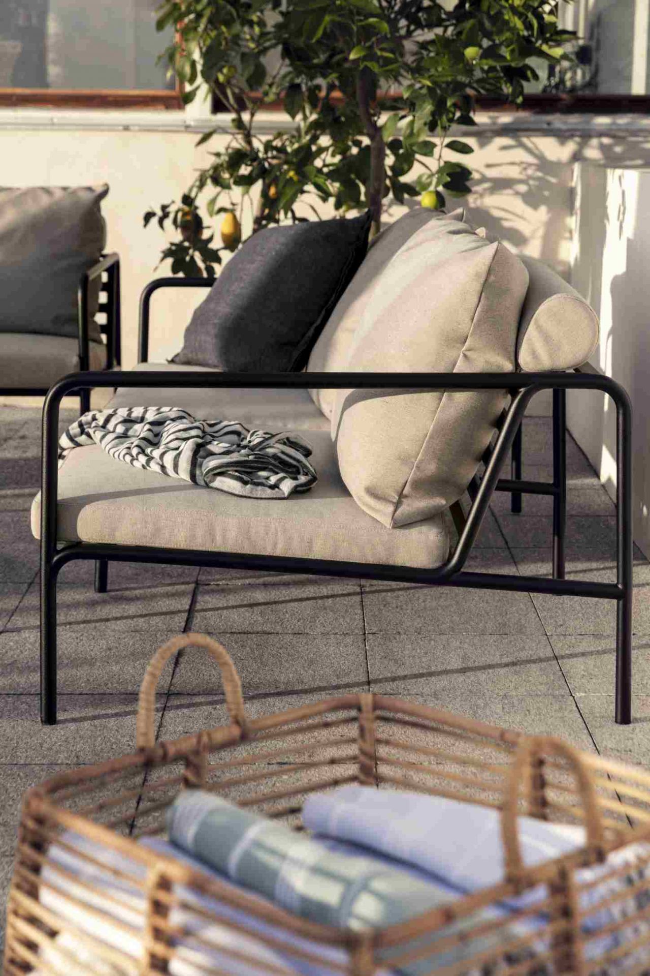Avon 2-Sitzer Sofa Outdoor von Houe mit Kissen und Decke auf einer Terrasse.