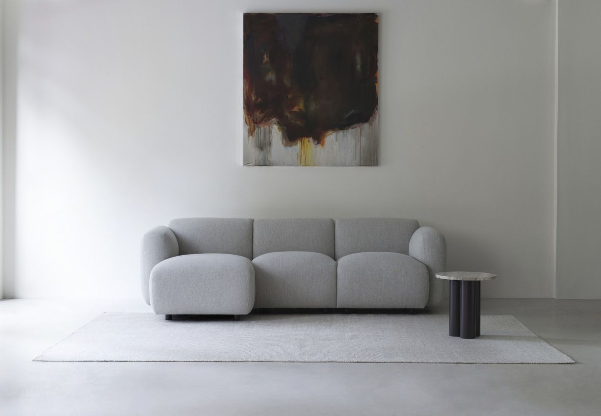 Normann Copenhagen Dit Coffee Table Beistelltisch aus Marmor neben grauem Sofa auf hellem Teppich.