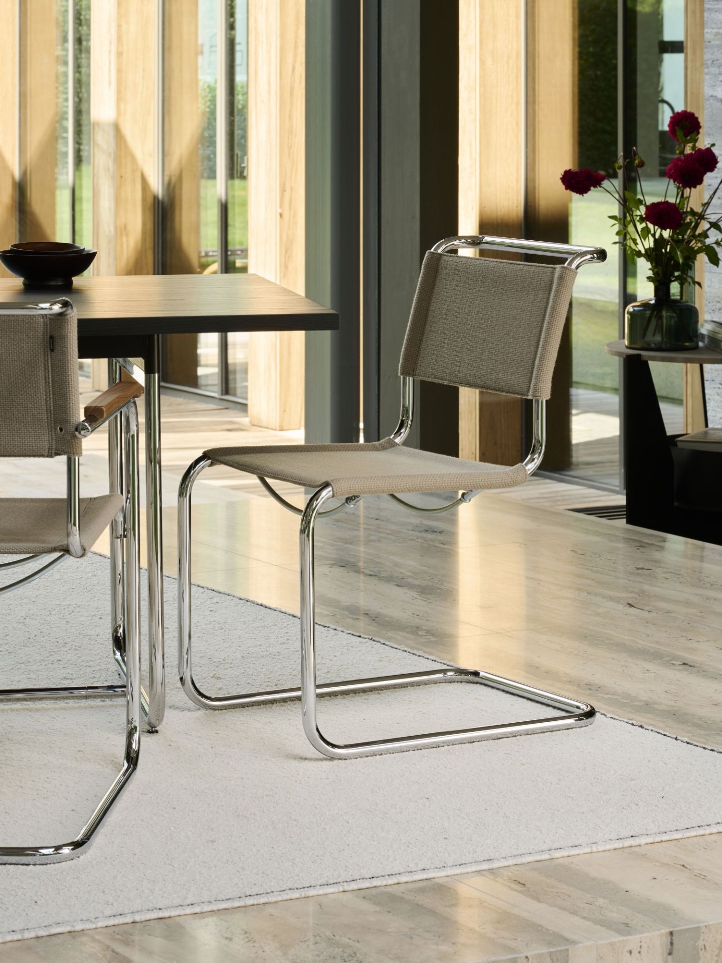 Thonet S 33 V Freischwinger Stuhl mit beigem Stoffbezug und verchromtem Stahlrohrgestell im modernen Esszimmer.