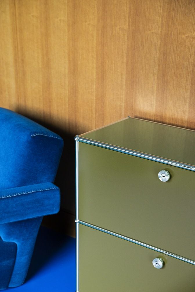 Detailaufnahme eines olivgrünen USM Haller Highboards mit Klapptüren, Teil eines modularen Möbelbausystems.