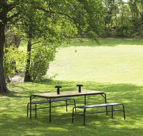 Normann Copenhagen Vig Table Outdoor Esstisch mit Bänken auf einer grünen Wiese.