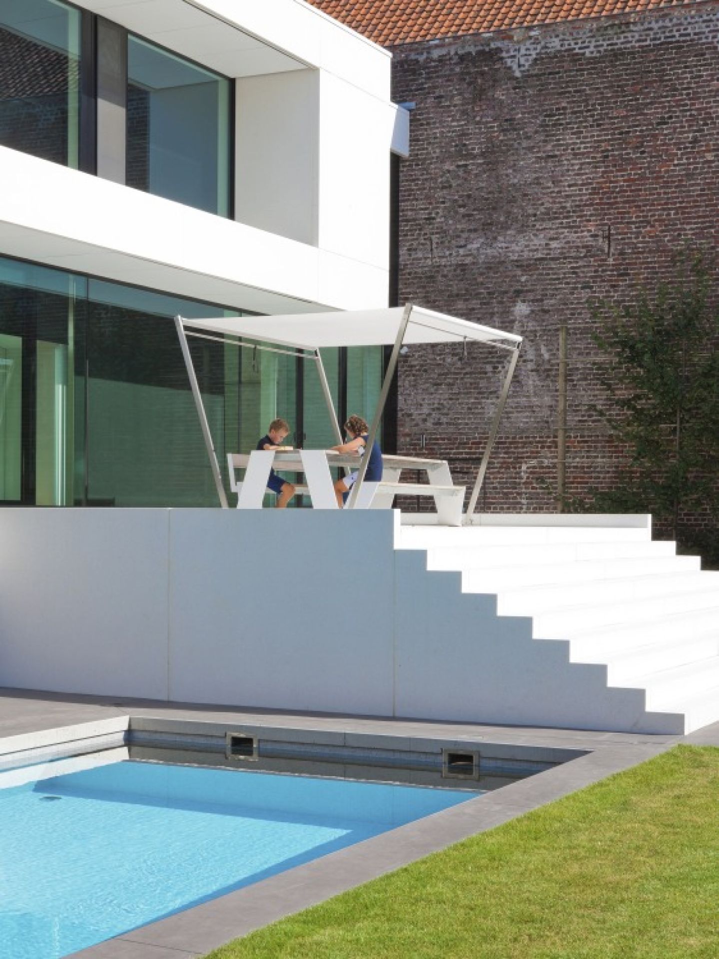 Hopper Picnic Bank von Extremis im Außenbereich mit spielenden Kindern und Pool.