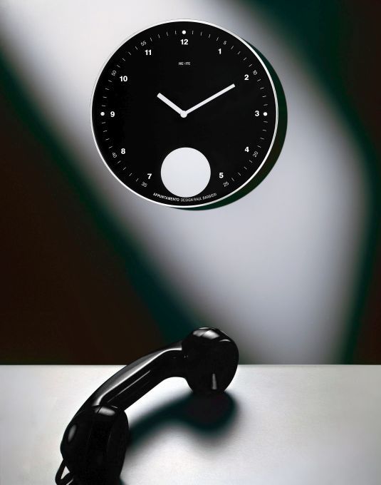 Schwarze Appuntamento Wanduhr von Rexite mit Pendel und Telefonhörer im minimalistischen Design.