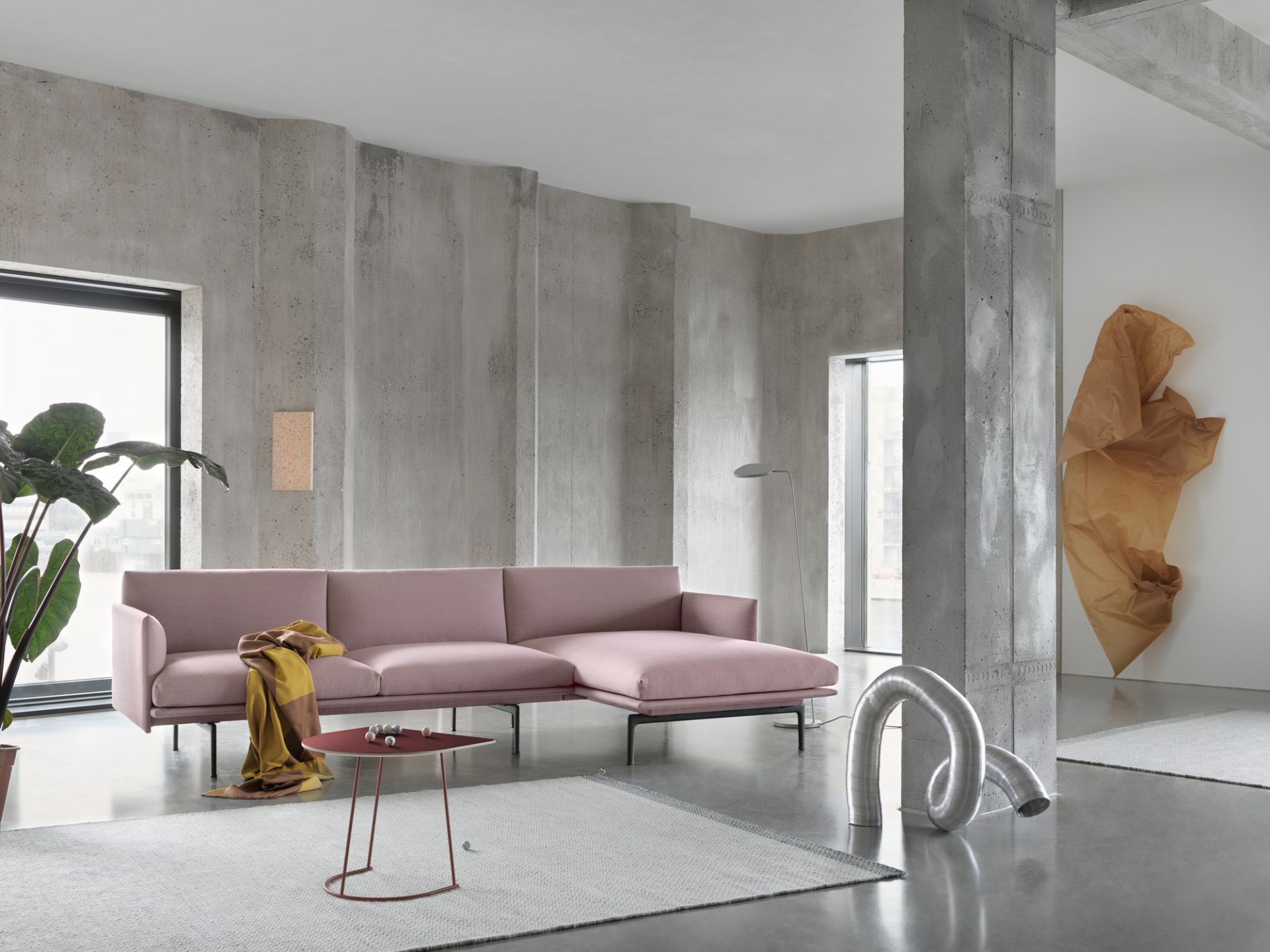 Rosa Outline Sofa mit Chaiselongue von Muuto in modernem Wohnzimmer mit Betonwänden.