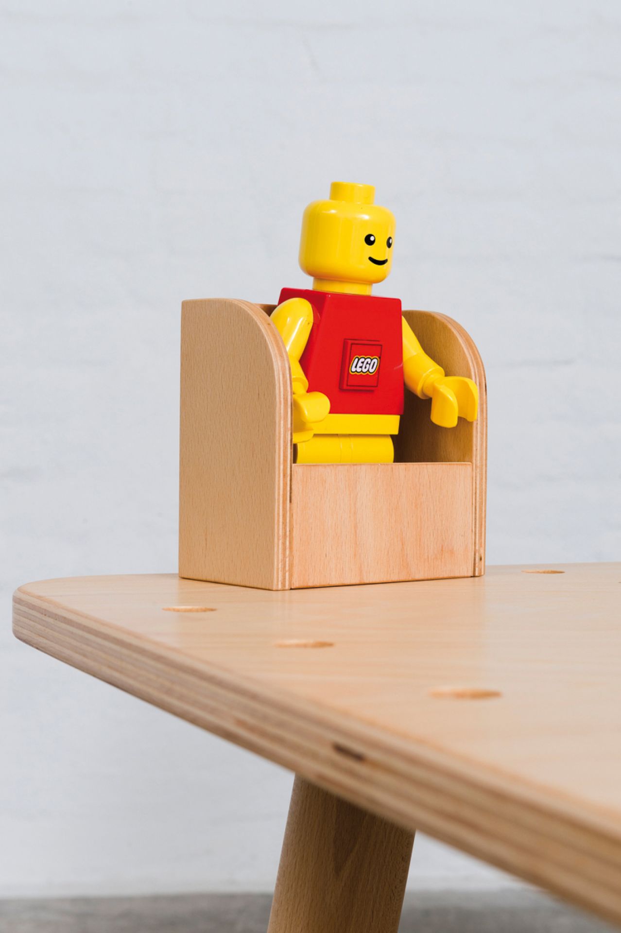 Growing Table Buche: Lego-Figur sitzt in einer kleinen Holzbox auf dem Kindertisch.