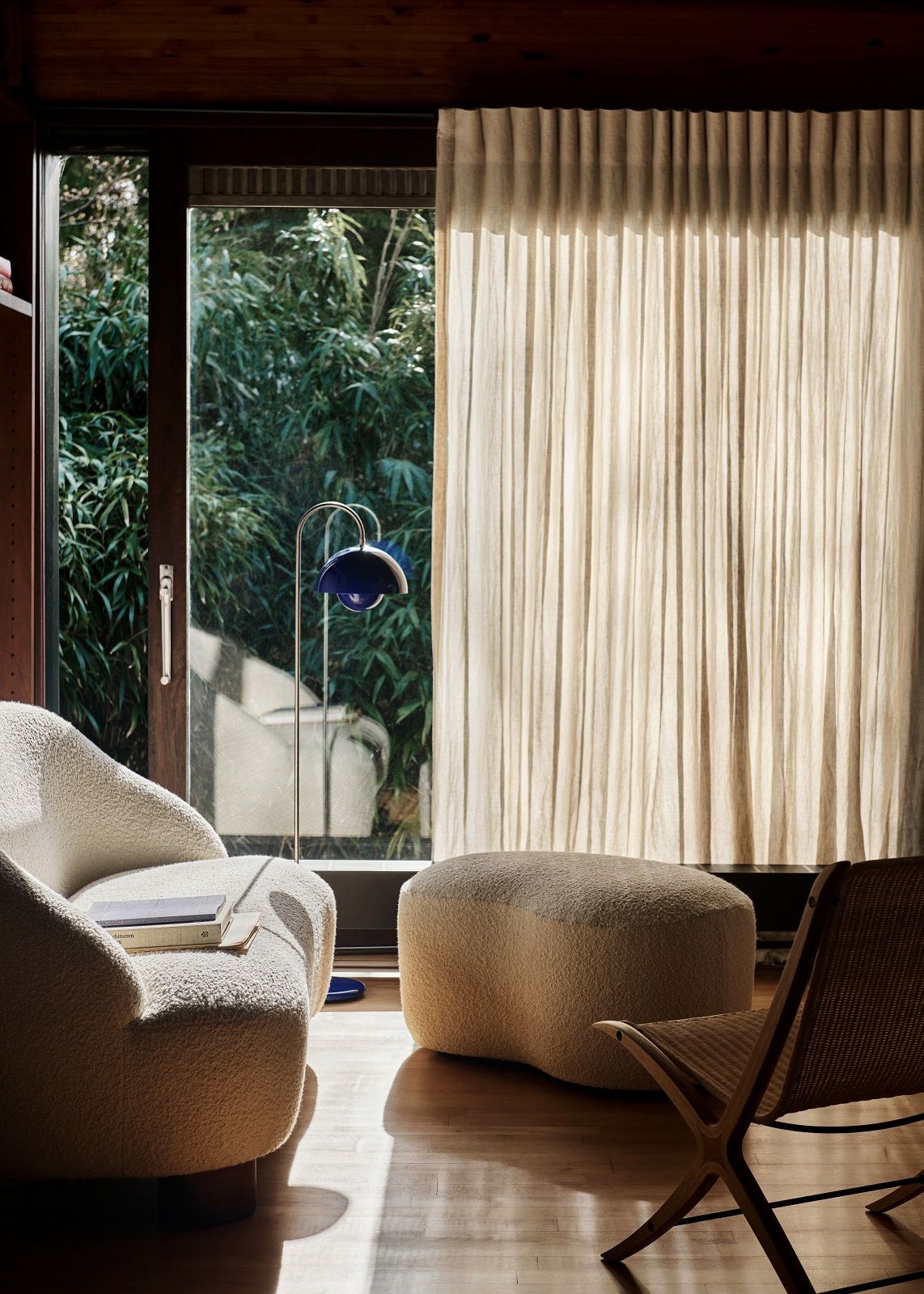 Beiger Margas LC5 Pouf Hocker von AndTradition im modernen Wohnzimmer mit Sessel und Vorhang.