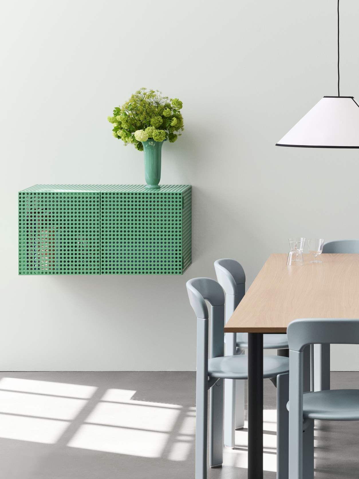 Grünes Hay Perforated Cabinet Wall Sideboard im modernen Esszimmer mit Tisch und Stühlen.
