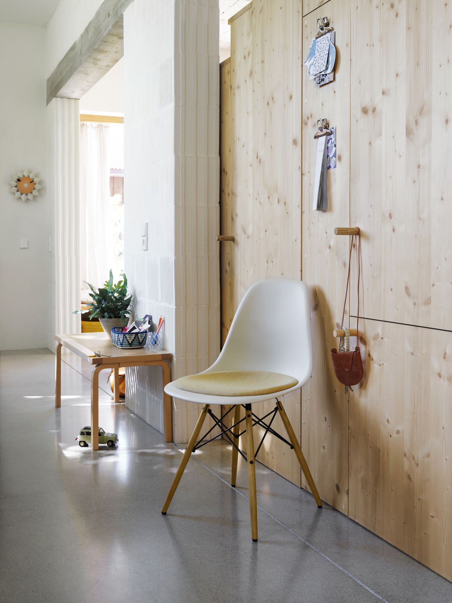 Weißer Eames Fiberglass Chair DSW Stuhl mit gelbem Sitzpolster von Vitra im modernen Flur.