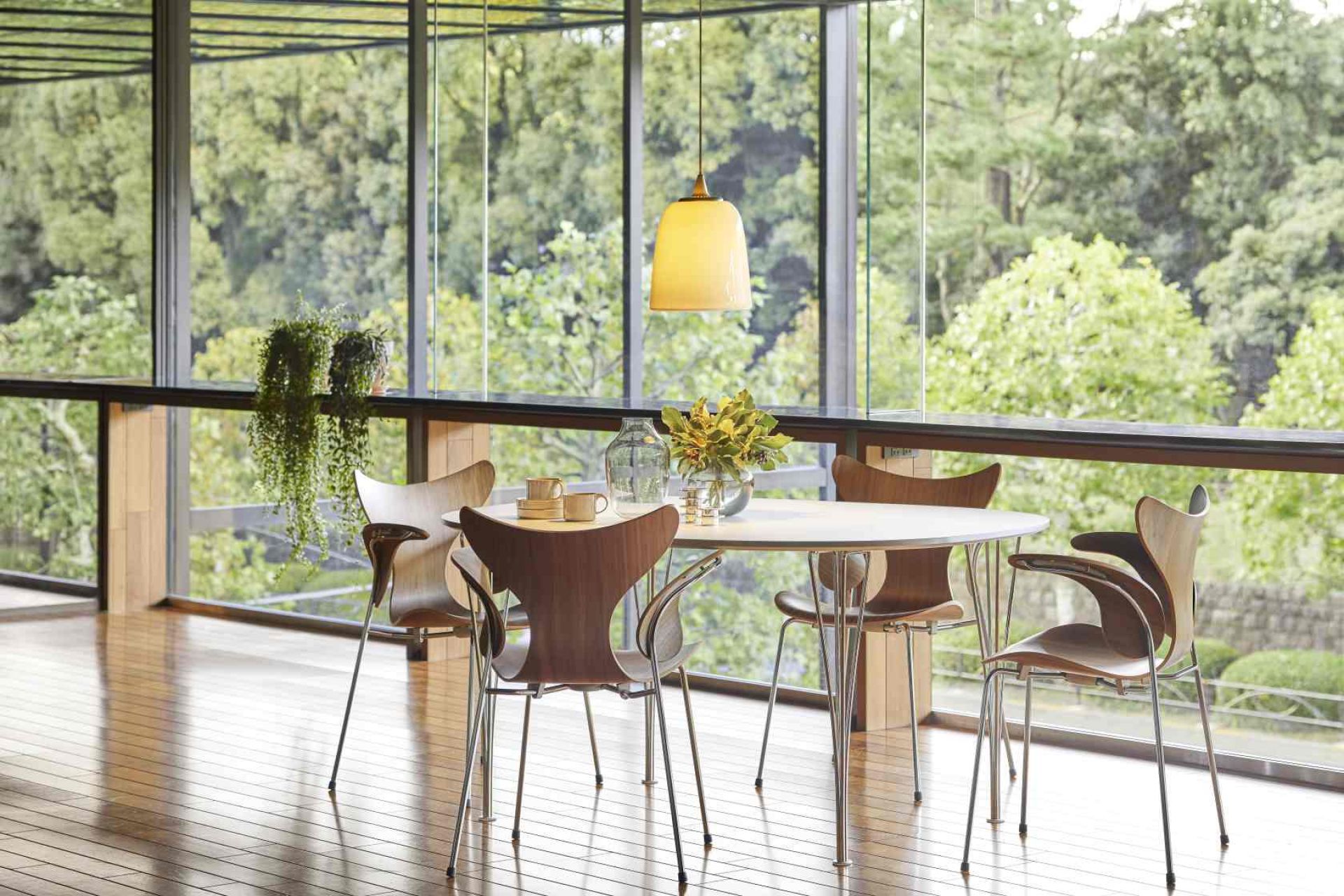 Fritz Hansen Lily Armlehnenstuhl 3208 aus Holz und Chrom in modernem Esszimmer mit Panoramafenster.
