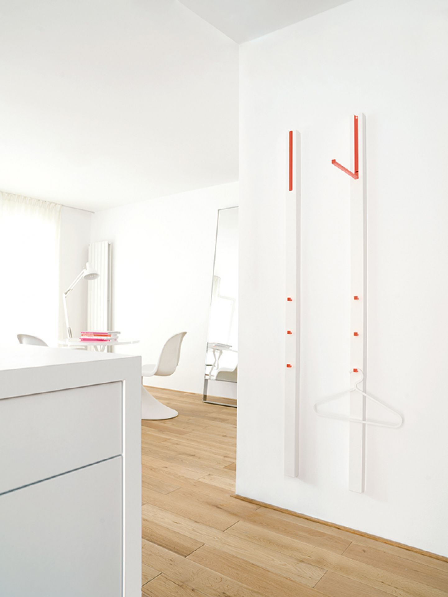 Weiße Line Garderobe von Schönbuch mit roten Akzenten an einer weißen Wand im minimalistischen Flur.